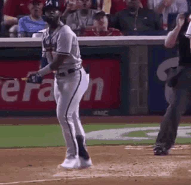 a baseball player is swinging a bat at a pitch while a referee looks on .