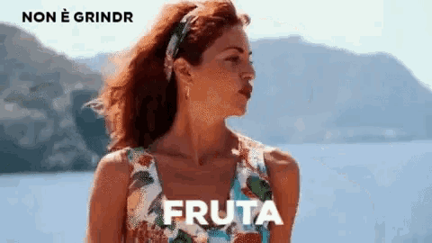 a woman in a colorful dress is standing in front of a body of water with the word fruta written on the bottom .