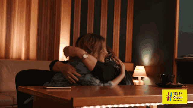a man and woman hugging in front of a sign that says 101.3 miami