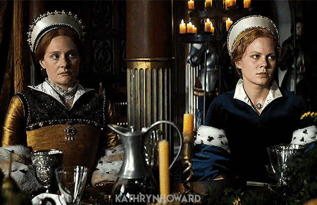 two women are sitting at a table with candles and the name kathryn howard on the bottom right