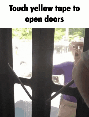 a woman in a purple shirt is touching yellow tape to open a door