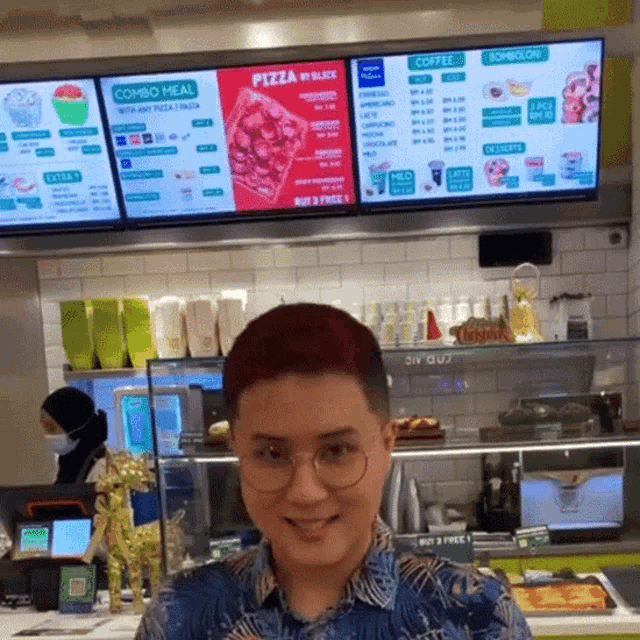 a man stands in front of a pizza menu in a restaurant