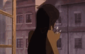 a woman is smoking a cigarette in front of a window in a city .