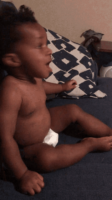 a baby in a diaper sits on a couch
