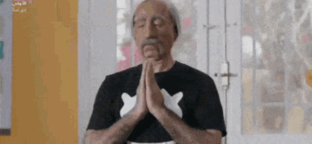 a man with a mustache is praying with his eyes closed .