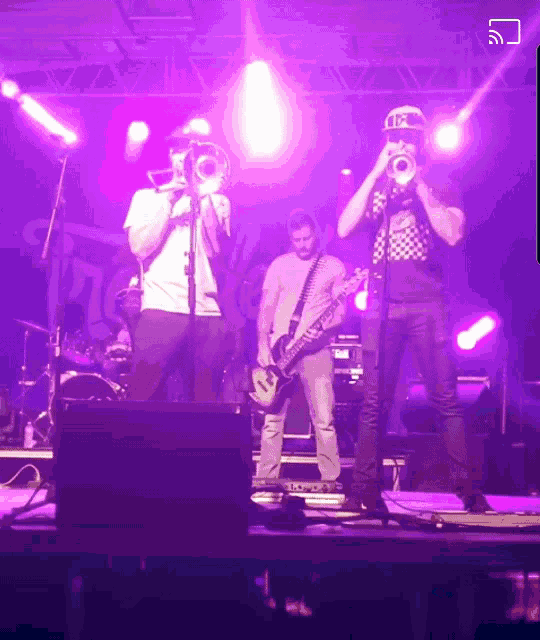 a man playing a trumpet and a man playing a guitar on a stage with purple lights