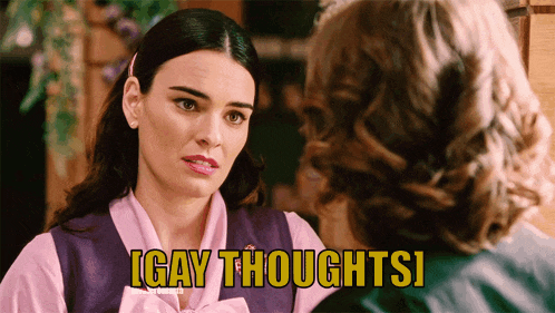 a woman in a pink shirt is talking to another woman in a purple vest with the words igay thoughtsi above her