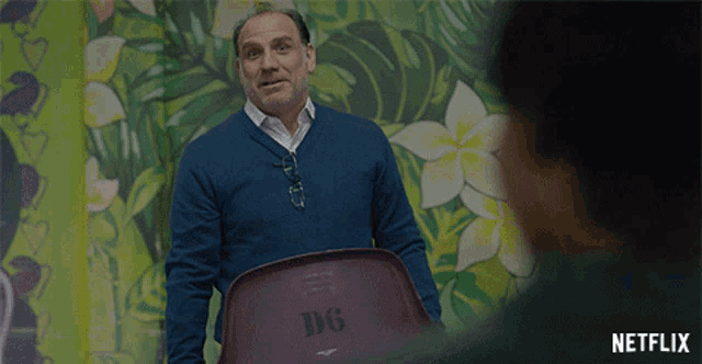 a man in a blue sweater is holding a chair that says dg on it