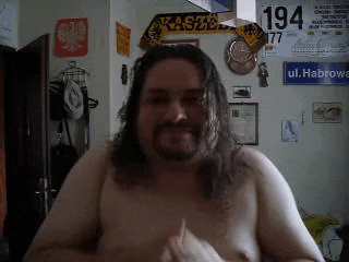 a shirtless man with long hair and a beard is standing in a room .