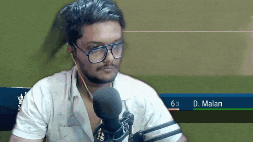 a man wearing glasses and ear buds stands in front of a microphone with the name d. malam on the bottom right
