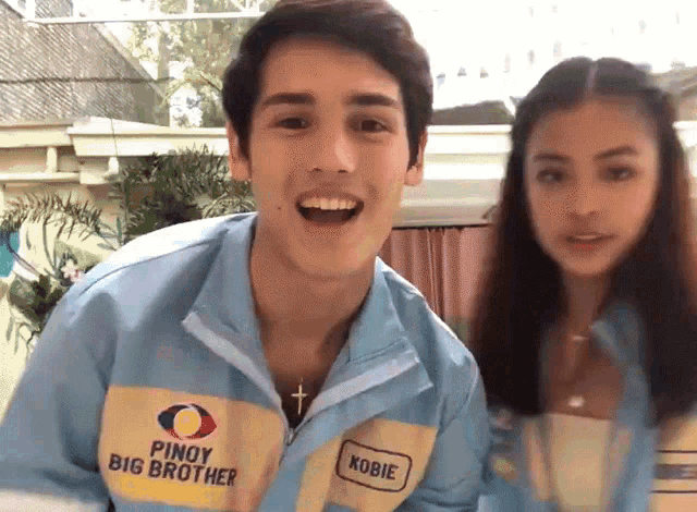 a man and a woman are posing for a picture and the man is wearing a jacket that says pinoy big brother