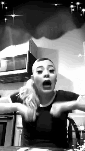 a woman in a black shirt is making a funny face in a kitchen .
