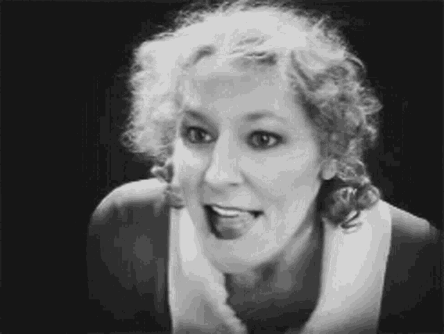 a black and white photo of a woman sticking her tongue out .