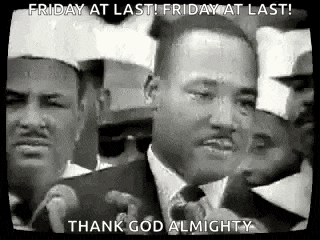 a black and white photo of martin luther king jr. speaking into a microphone in front of a crowd of people .