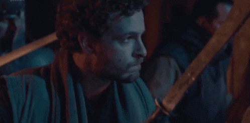a man with a scarf around his neck is holding a sword in his hand .