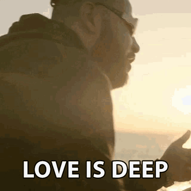 a man with a beard and sunglasses says love is deep while looking at his phone