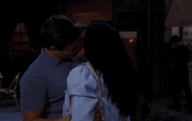 a man and woman are kissing in front of a brasserie