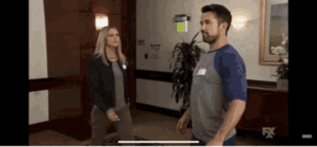 a man and a woman are standing next to each other in a hallway with the fx logo in the corner .