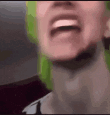a close up of a person 's face with green hair and a blurred background .