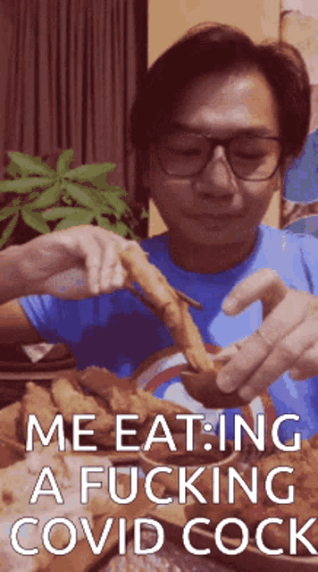 a man in a blue shirt is eating a piece of fried chicken