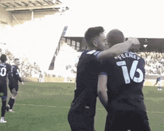 two soccer players are hugging and one has the number 16 on his jersey