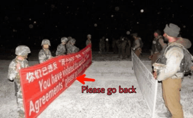 a group of soldiers are holding a banner that says please go back
