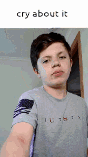 a young boy is taking a selfie with a caption that says cry about it .