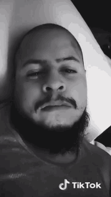 a man with a beard is laying on a bed and looking at the camera .