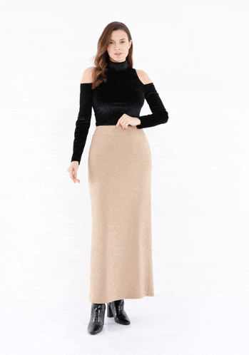 a woman wearing a black off the shoulder top and a long beige skirt