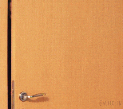 a woman in a red sweater is peeking out of a doorway .
