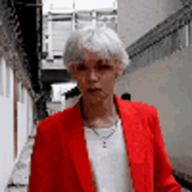 a woman wearing a red jacket and a white shirt is walking down a street .