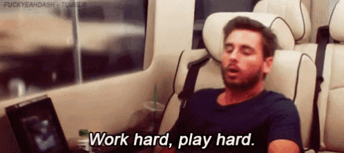 a man is sitting in a car with his eyes closed and the words `` work hard , play hard '' written on the screen .