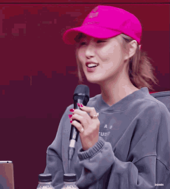 a woman wearing a pink hat holds a microphone in her hand