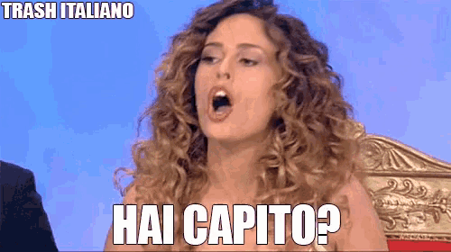 a woman with curly hair is sitting in a chair and says hai capito