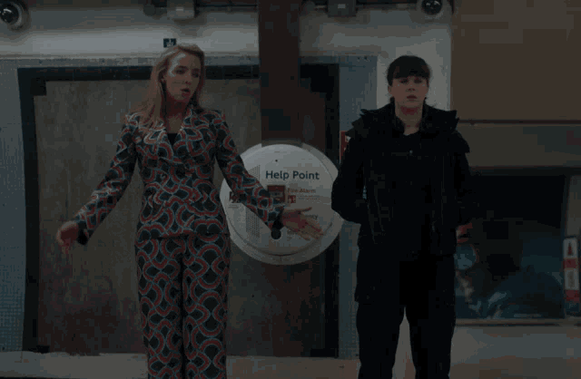 two women are standing in front of a help point