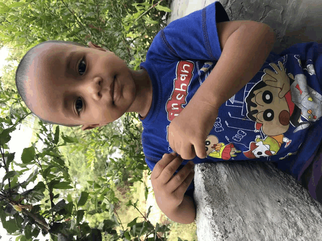 a young boy wearing a blue shirt that says shin chan