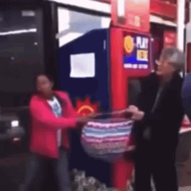 a woman in a pink jacket is holding a purse in front of a vending machine that says o play