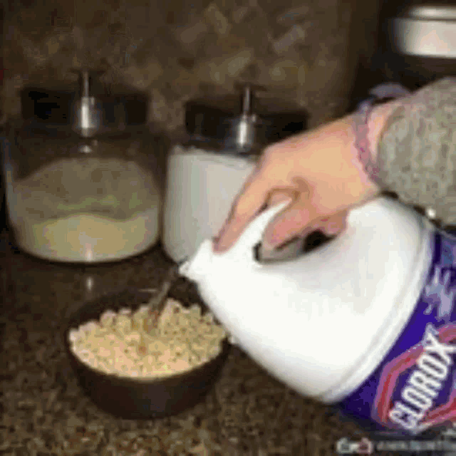 a person pouring clorox into a bowl of macaroni and cheese