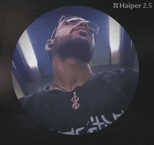 a man with glasses is eating a slice of cucumber and haiper 2.5 is visible in the corner