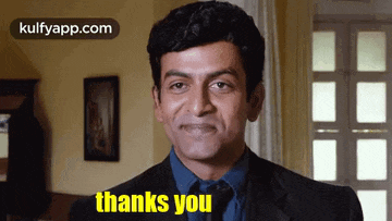 a man in a suit and tie is giving a thank you sign .