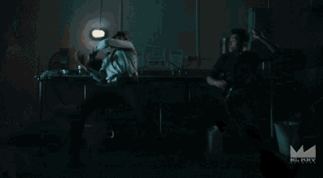 a man is holding a frying pan over another man 's head with a mummy logo in the corner