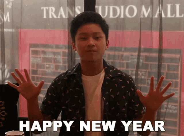 a young man says happy new year in front of a window