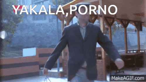 a man in a suit and hat is dancing in front of a sign that says yakala porno