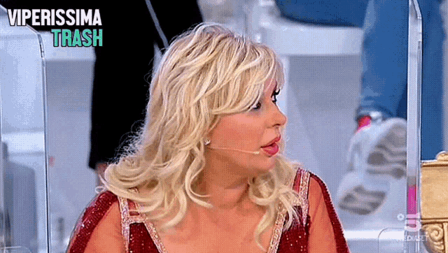 a woman in a red dress is talking into a microphone with the words viperissima trash behind her