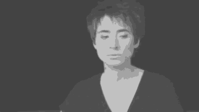 a black and white photo of a woman with short hair and a serious look on her face .