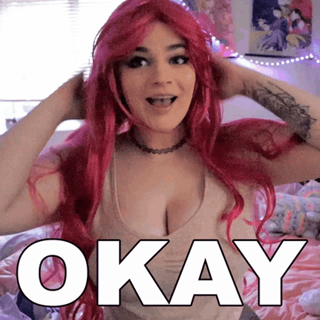 a woman with red hair is wearing a tank top that says okay on it