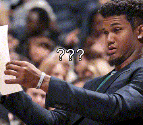 a man in a suit holds a piece of paper in front of a crowd with a question mark on his face