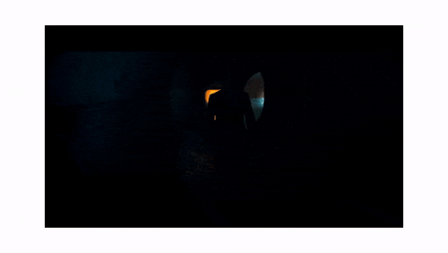 a man in a suit and tie is standing in a dark tunnel .