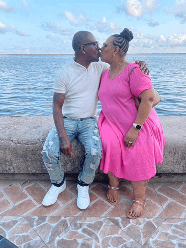a woman in a pink dress kisses a man in a white shirt