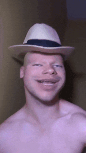 a man without a shirt is wearing a white hat and making a funny face